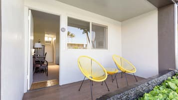 A room with a wooden floor, a window, and two yellow chairs.