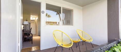A room with a wooden floor, a window, and two yellow chairs.