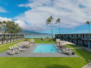 A pool area with lounge chairs and a view of the ocean. - Maui Seaside Hotel (Kahului)