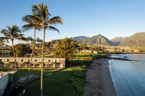 A coastal hotel with a pool, palm trees, and a view of mountains. - Maui Seaside Hotel (Kahului)