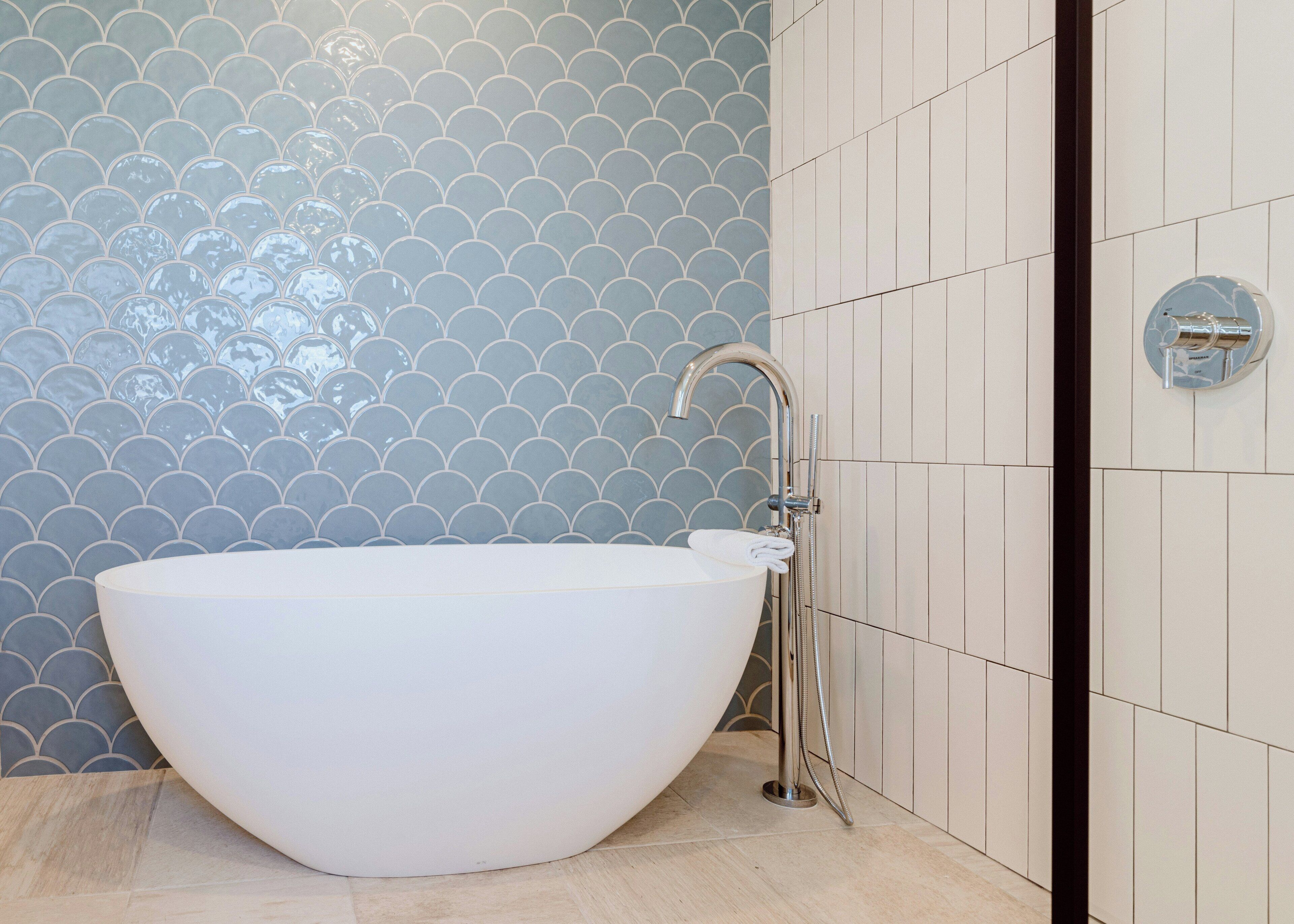 A modern bathroom with a freestanding bathtub, a handheld showerhead, and a wall-mounted faucet.
