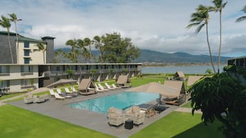 Una piscina al aire libre, sombrillas, sillones reclinables de piscina
