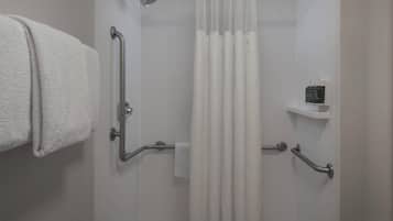 A shower with a grab bar, a towel rack, and a shower control panel.