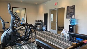 Ein Fitnessstudio mit Laufbändern, einer Spiegelwand und einem Wasserspender.