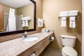 A bathroom with a granite sink, a mirror, a toilet, and towel racks.