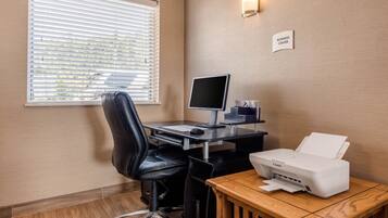 A business center with a desk, computer, printer, and a sign indicating the location.