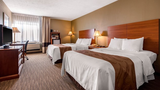 A hotel room with two beds, a desk, and a TV.