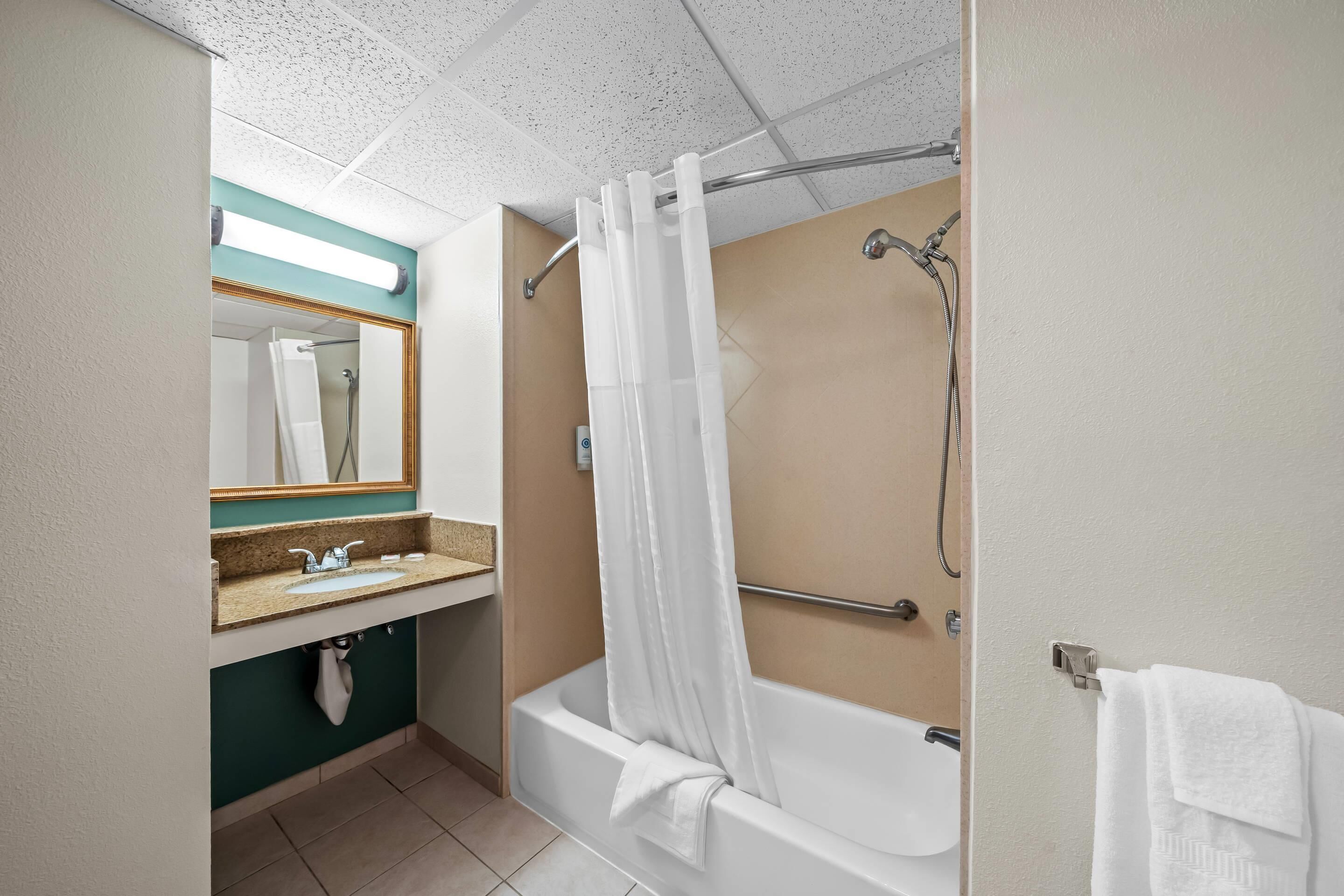 A bathroom with a bathtub, a shower, a sink, and a mirror.