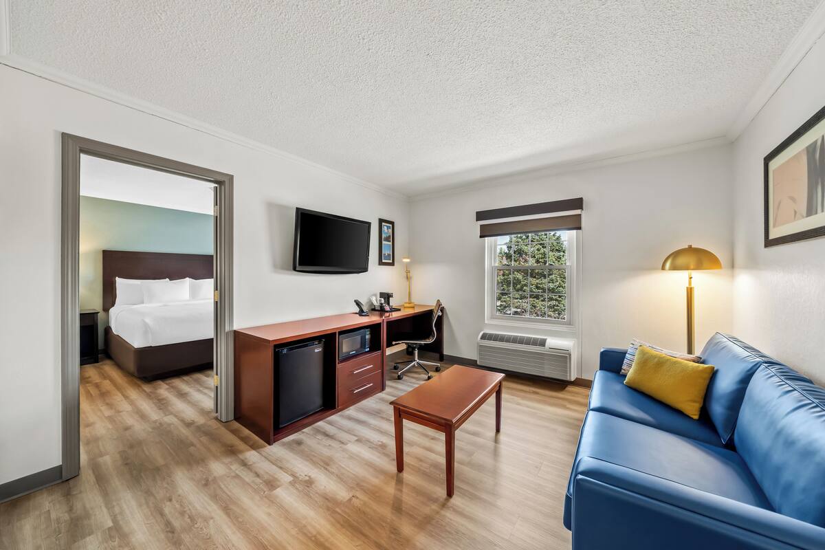 Une chambre d’hôtel avec un lit, un bureau, une chaise et un canapé bleu.