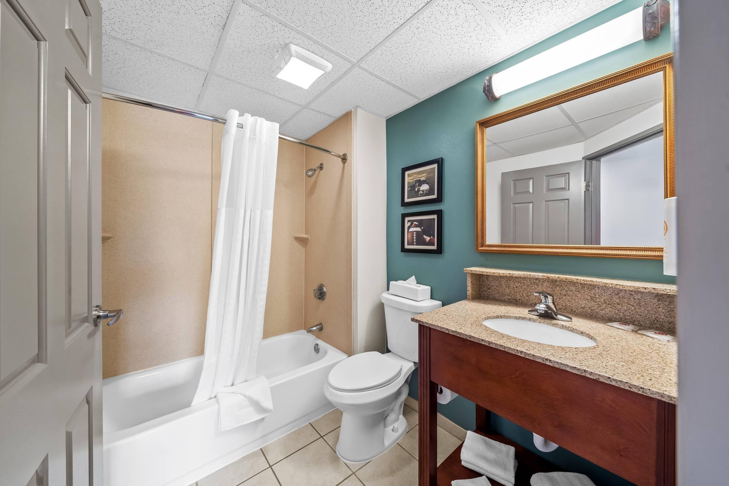 A bathroom with a bathtub, toilet, and sink, with a mirror above the sink.
