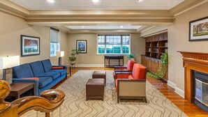 A spacious living room with a blue sofa, red armchair, and a fireplace.
