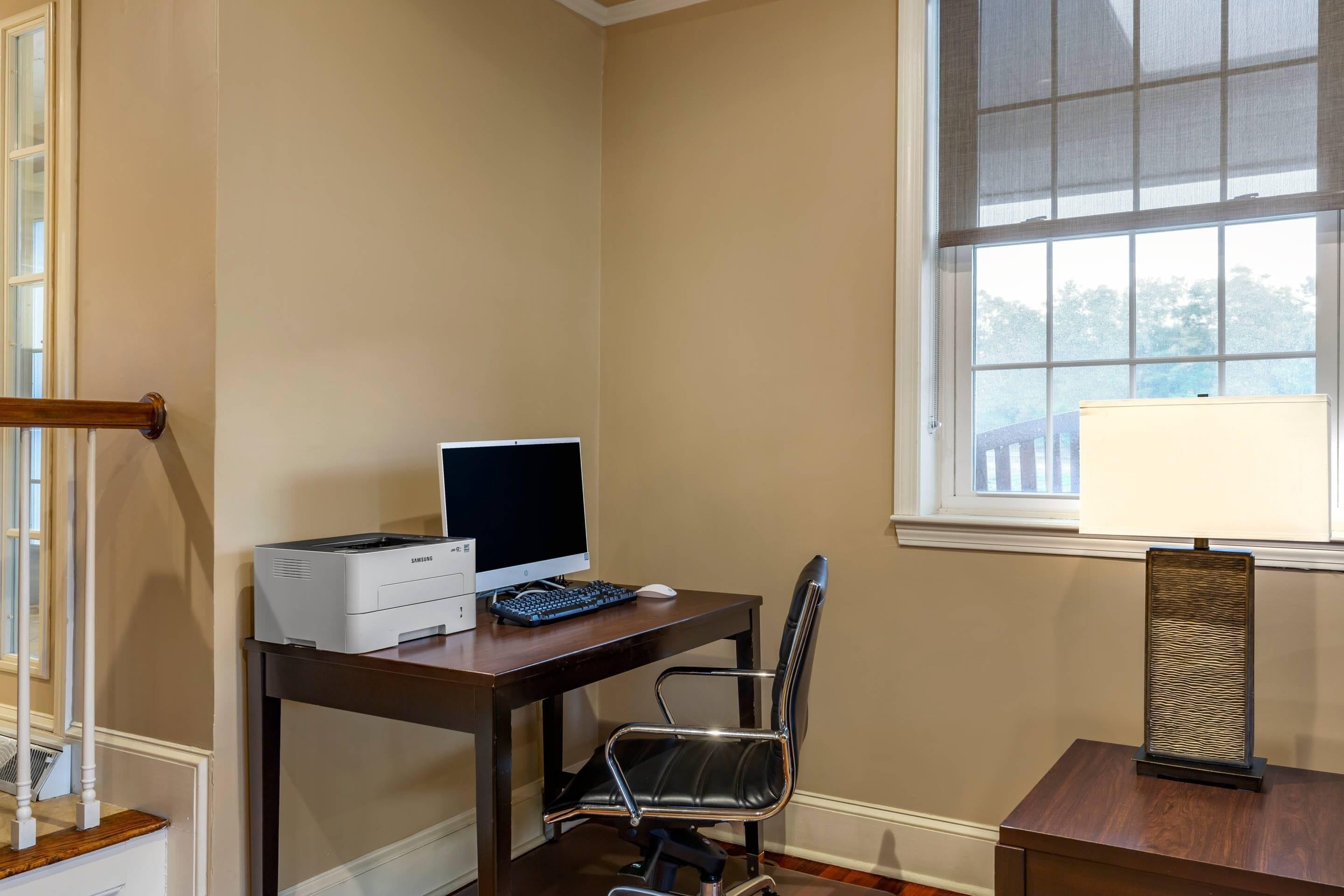 Une pièce comprenant un bureau, une chaise, une imprimante, un ordinateur et une lampe.