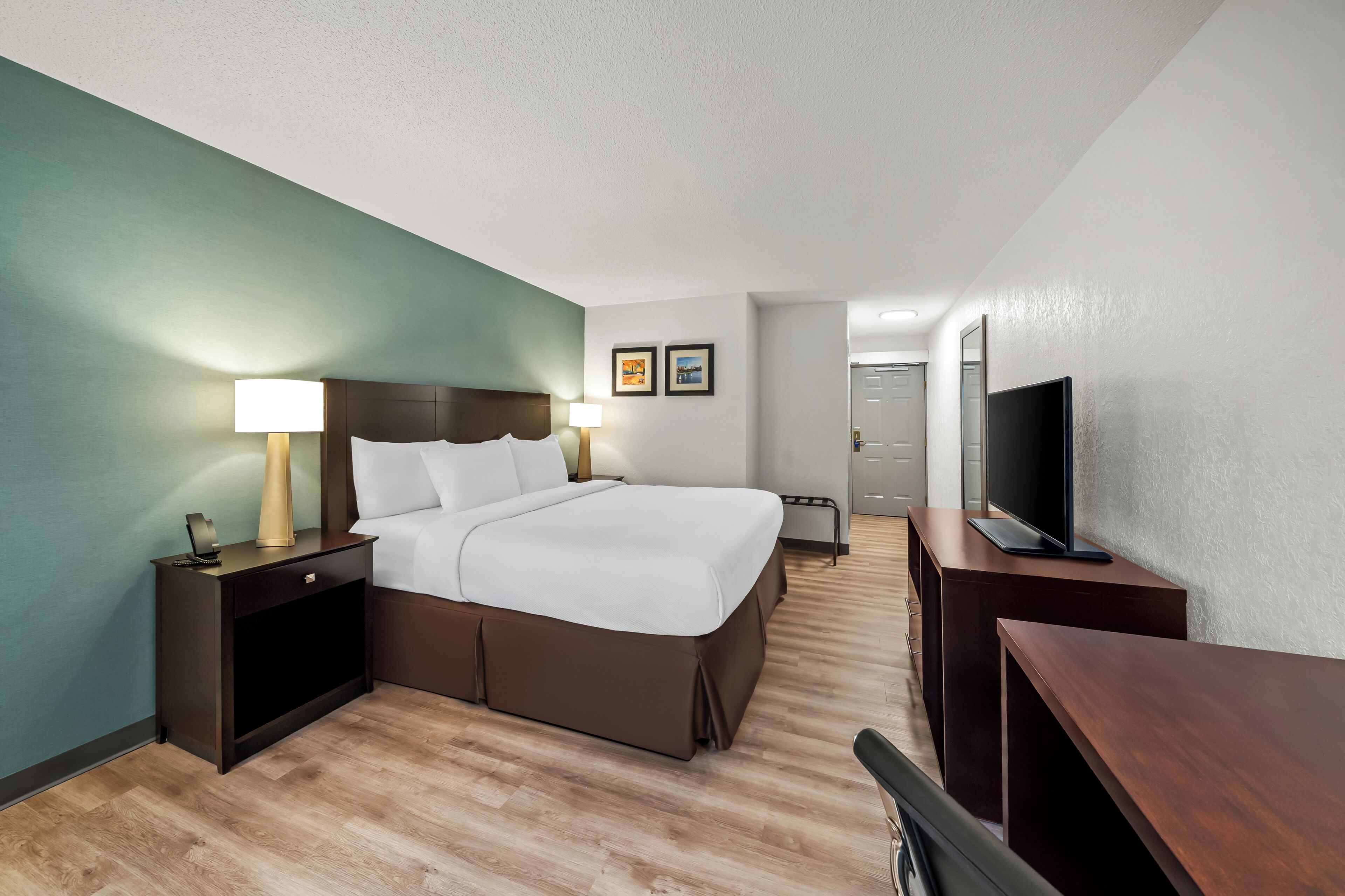 Une chambre d’hôtel avec un lit, des tables de chevet, une télévision et un bureau.