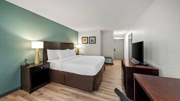 Une chambre d’hôtel avec un lit, des tables de chevet, une télévision et un bureau.