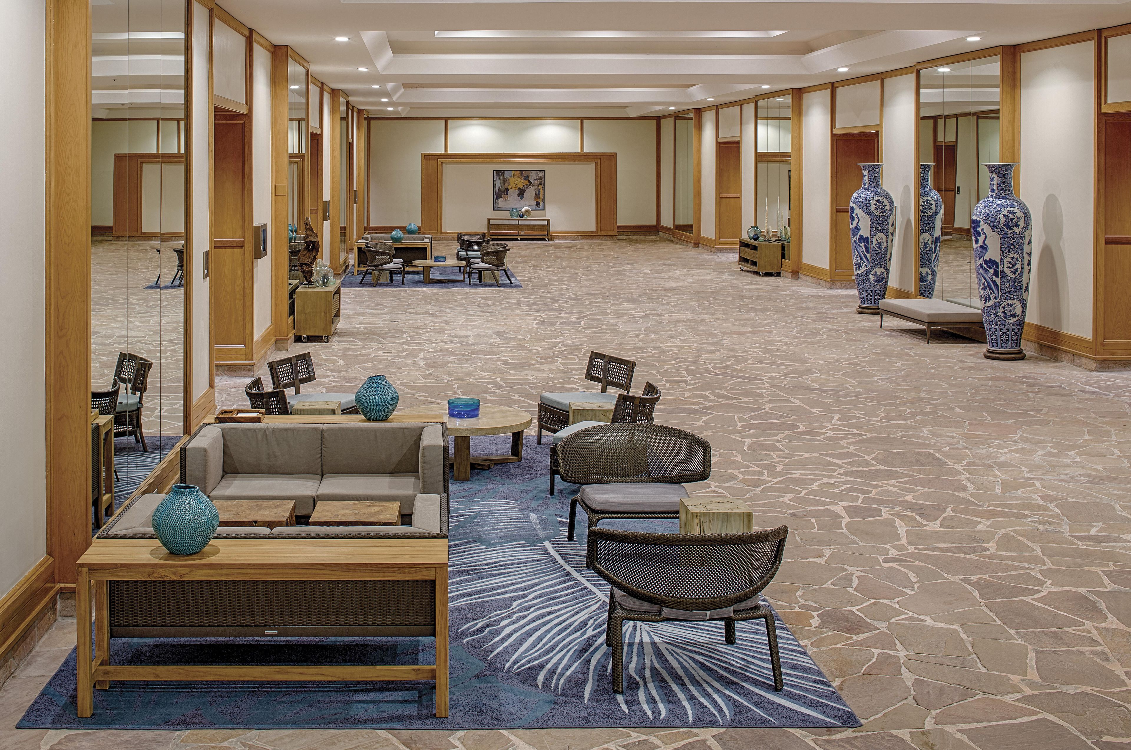 A hotel lobby with a seating area featuring sofas and chairs, a coffee table, and decorative vases.