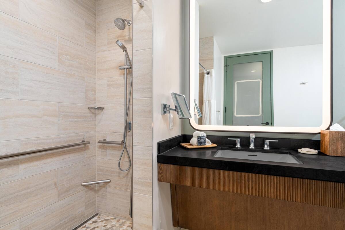 A modern bathroom with a shower, a sink, and a large mirror.