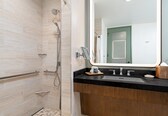A modern bathroom with a shower, a sink, and a large mirror.