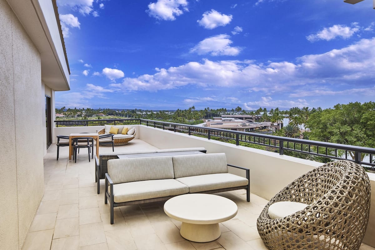 A balcony with a sofa, chairs, and a round table.