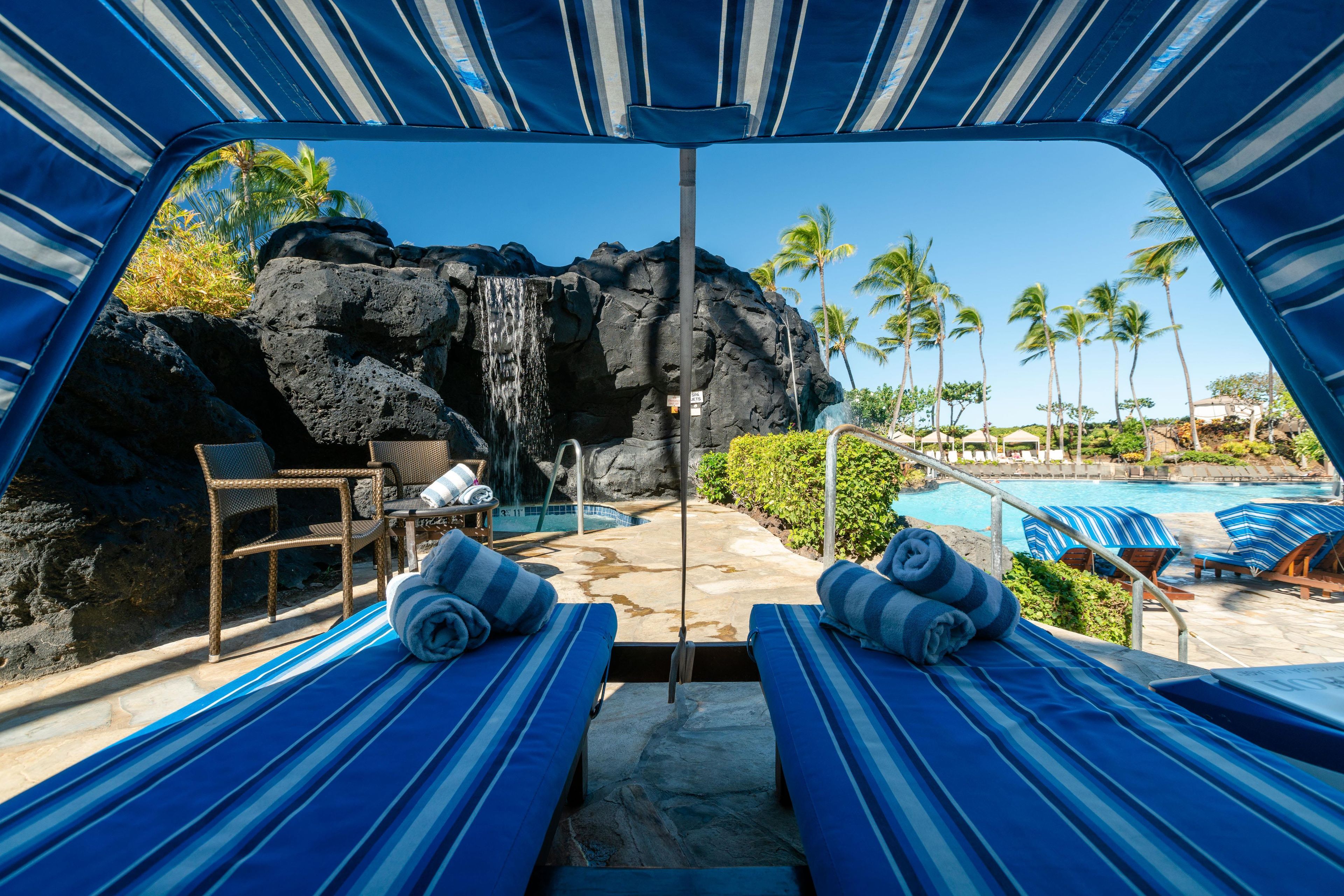 A poolside area with lounge chairs, a waterfall feature, and a clear view of the pool.