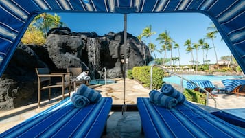 A poolside area with lounge chairs, a waterfall feature, and a clear view of the pool.
