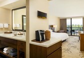 A hotel room with a large bed, a bathroom with a sink and mirror, a coffee maker, and a balcony with a view.