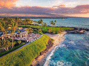 A coastal resort with a dining area, palm trees, and a view of the ocean. - Hilton Waikoloa Village (Waikoloa)