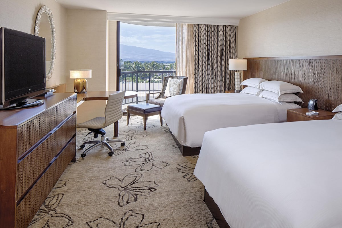 A hotel room with a TV, two beds, a desk, a chair, and a balcony with a view.