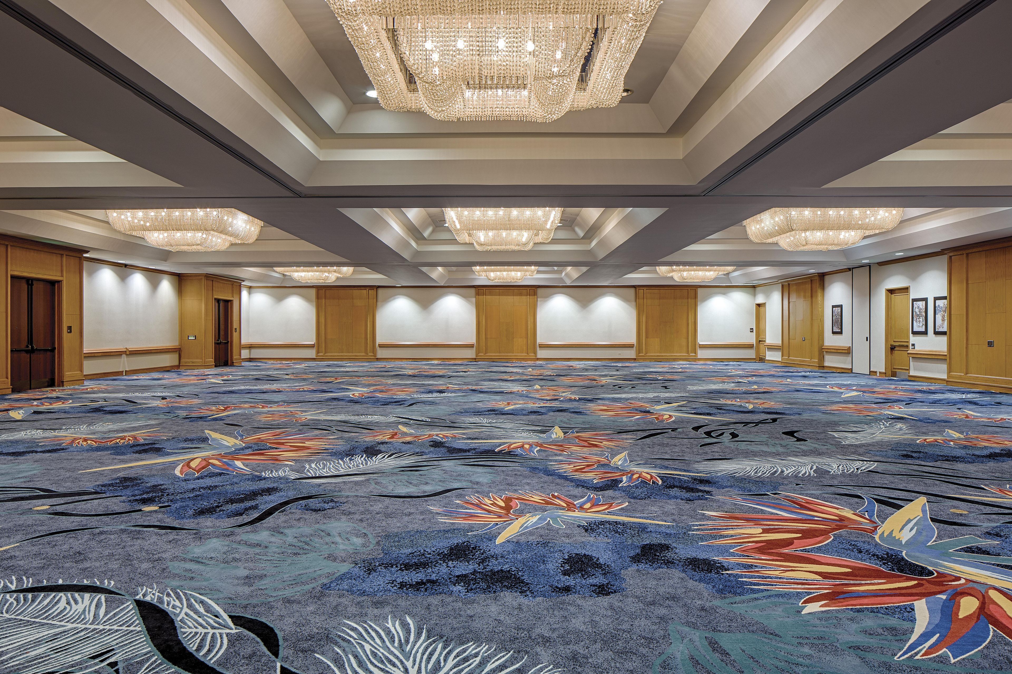 A large conference room with a patterned carpet, wooden paneling, and multiple chandeliers.