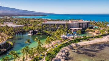 Um resort com um edifício grande, uma praia e um oceano azul e límpido.