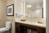 A modern bathroom with a toilet, sink, mirror, and shower.