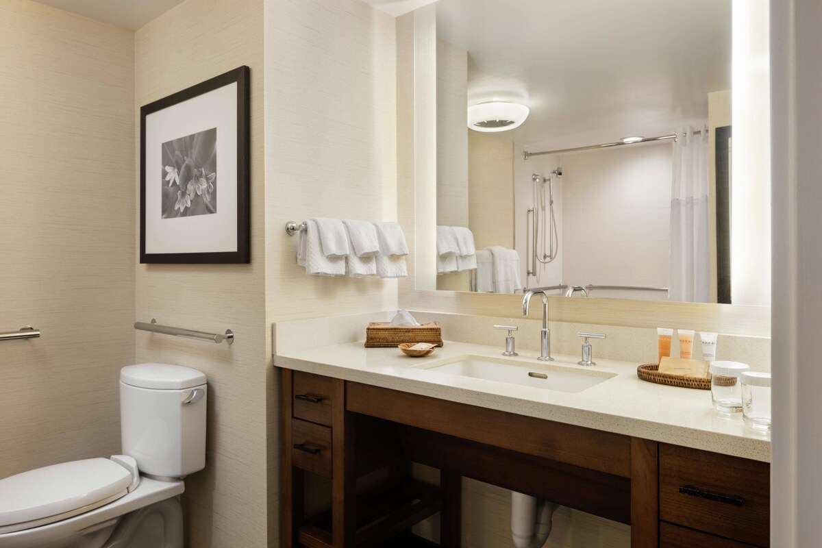 A modern bathroom with a toilet, sink, mirror, and shower.