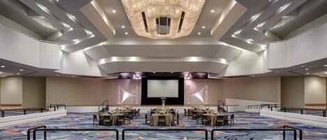 A large conference room with a high ceiling, a central chandelier, and a carpeted floor.