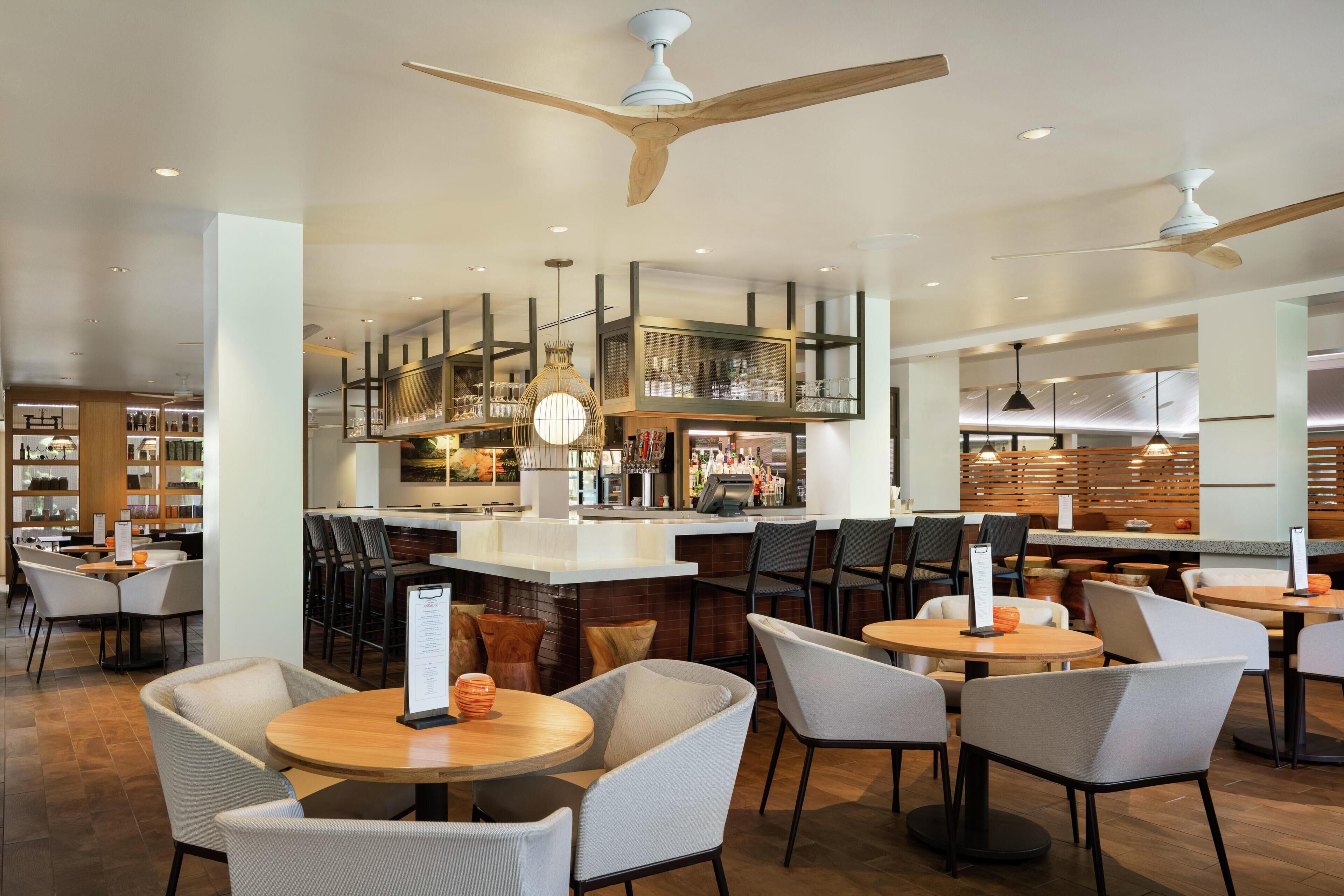 Un restaurante moderno con barra, techos altos y mobiliario contemporáneo.