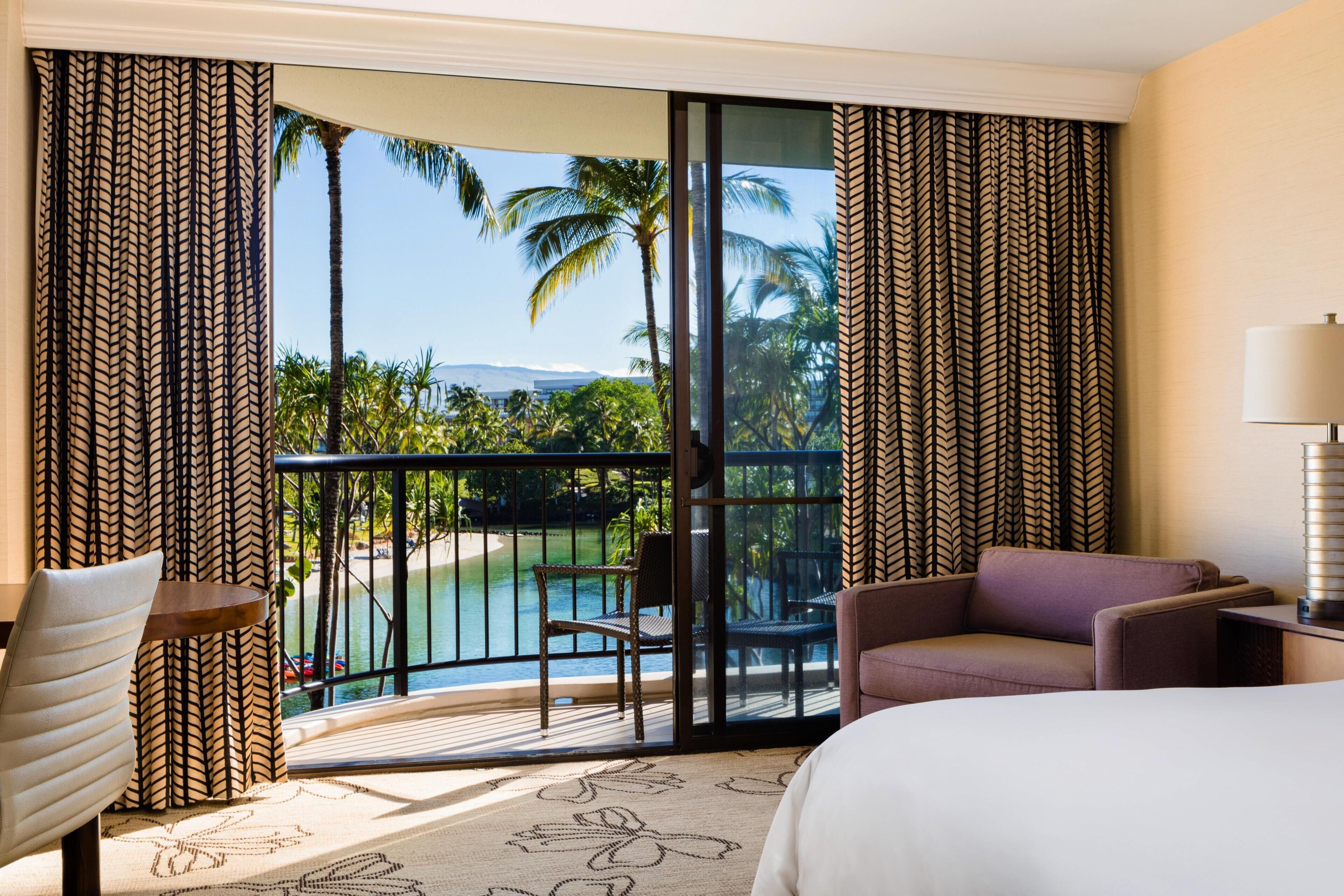 A hotel room with a large sliding glass door leading to a balcony with a pool view.