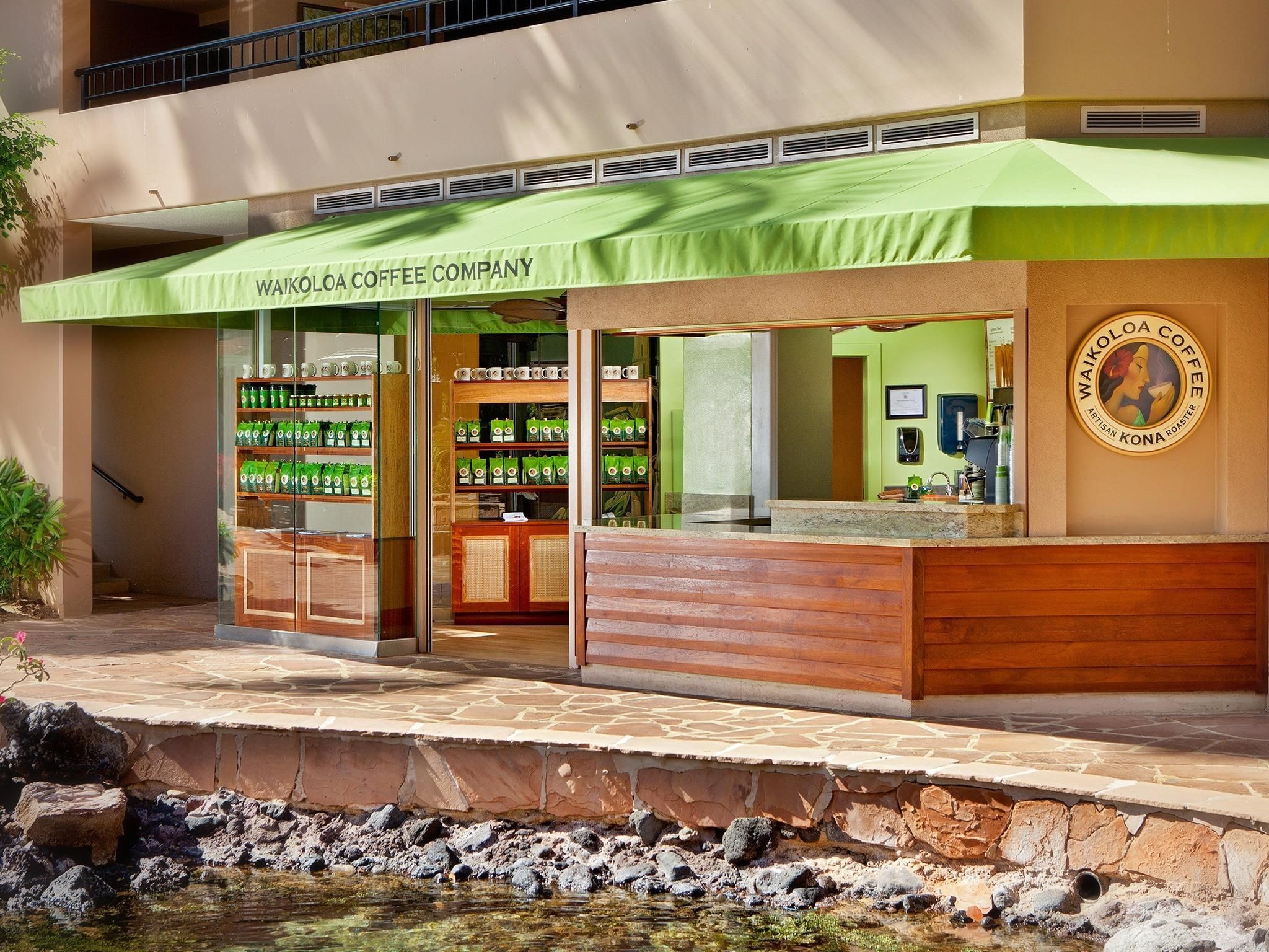 A coffee shop with a green awning, a counter, and shelves stocked with coffee products.