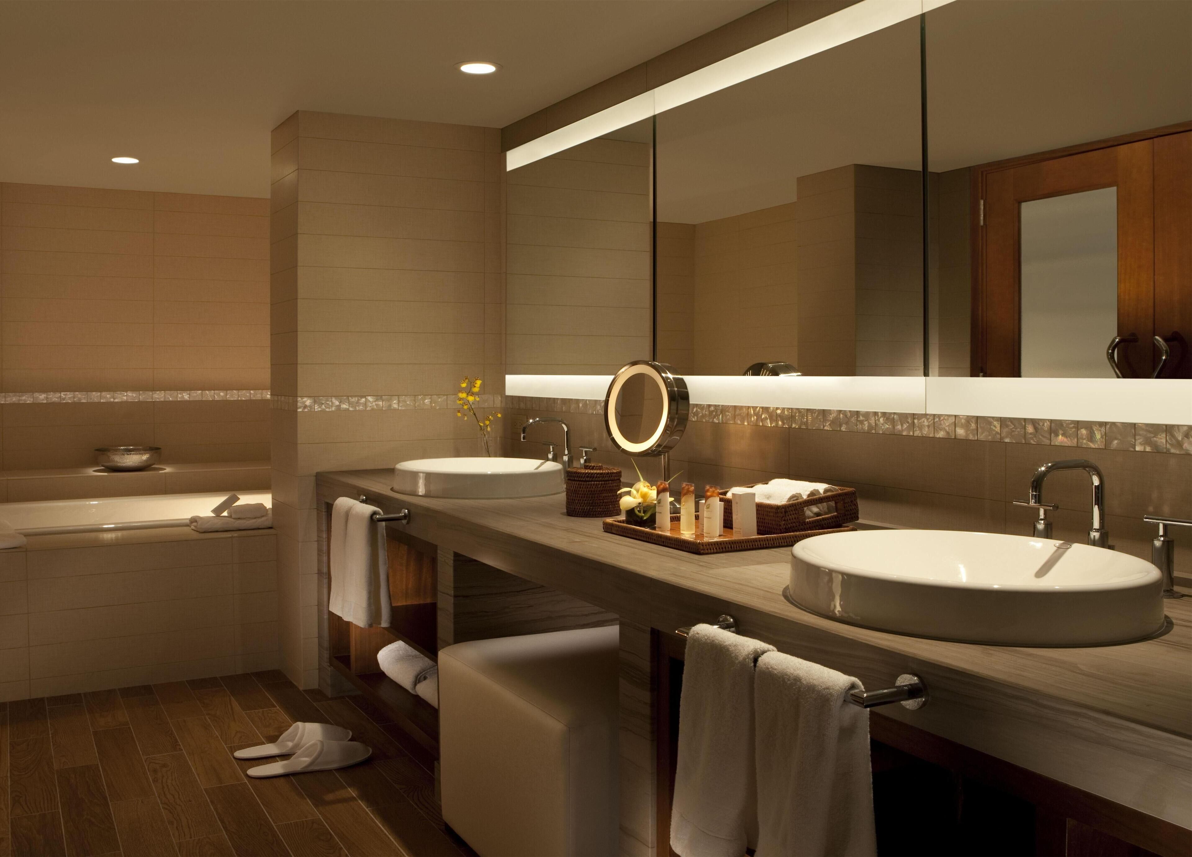 A modern bathroom with two sinks, a bathtub, and a large mirror.