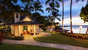 A house with a covered patio, a small tower, and a view of the ocean at dusk.