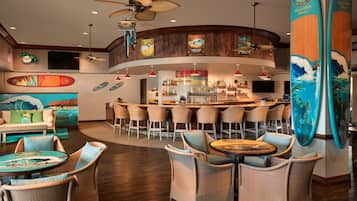 A bar area with high stools, a counter, and surfboard decorations.