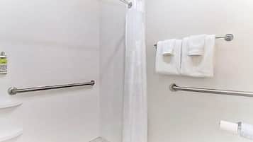 Un baño con ducha, barras de apoyo, inodoro y toallero con dos toallas.