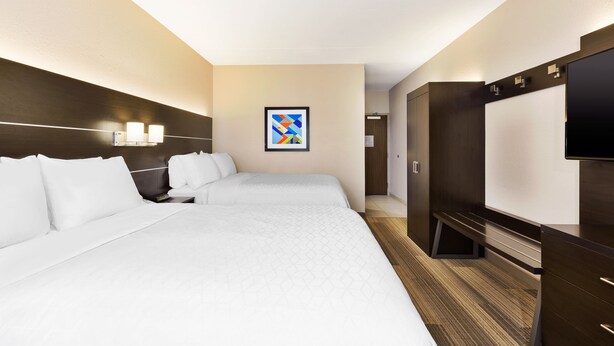 Een hotelkamer met twee bedden, een flatscreen televisie, een schilderij aan de muur en een houten vloer.