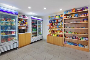 A snack and beverage kiosk with refrigerated display cases and shelves stocked with various snacks and drinks. - Holiday Inn Express Detroit-Warren by IHG (Warren)