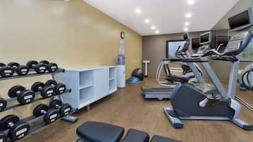Un gimnasio con jaulas de pesas, cintas de correr y pelotas de ejercicio.