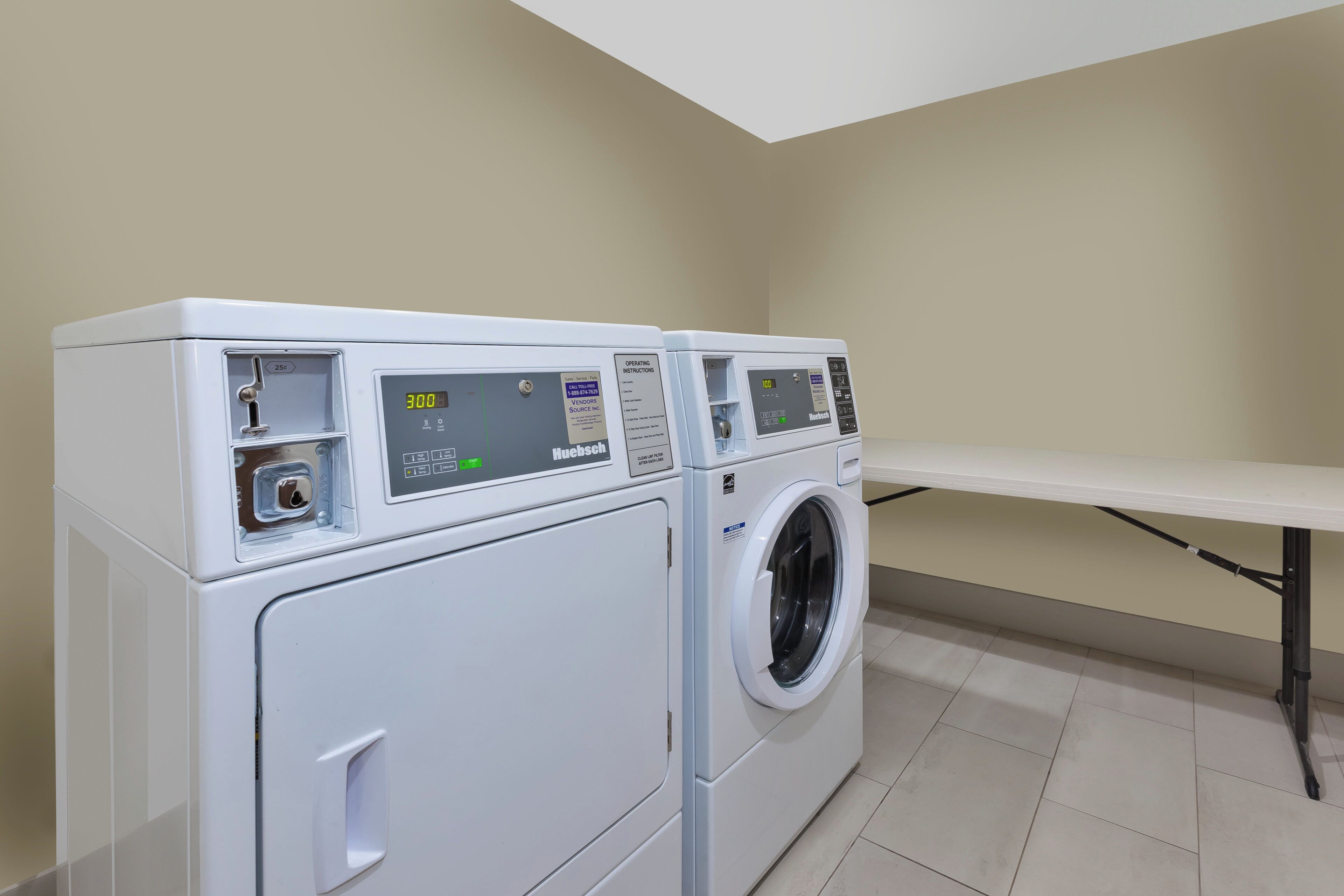 A laundry room with two front-loading washing machines and a table.