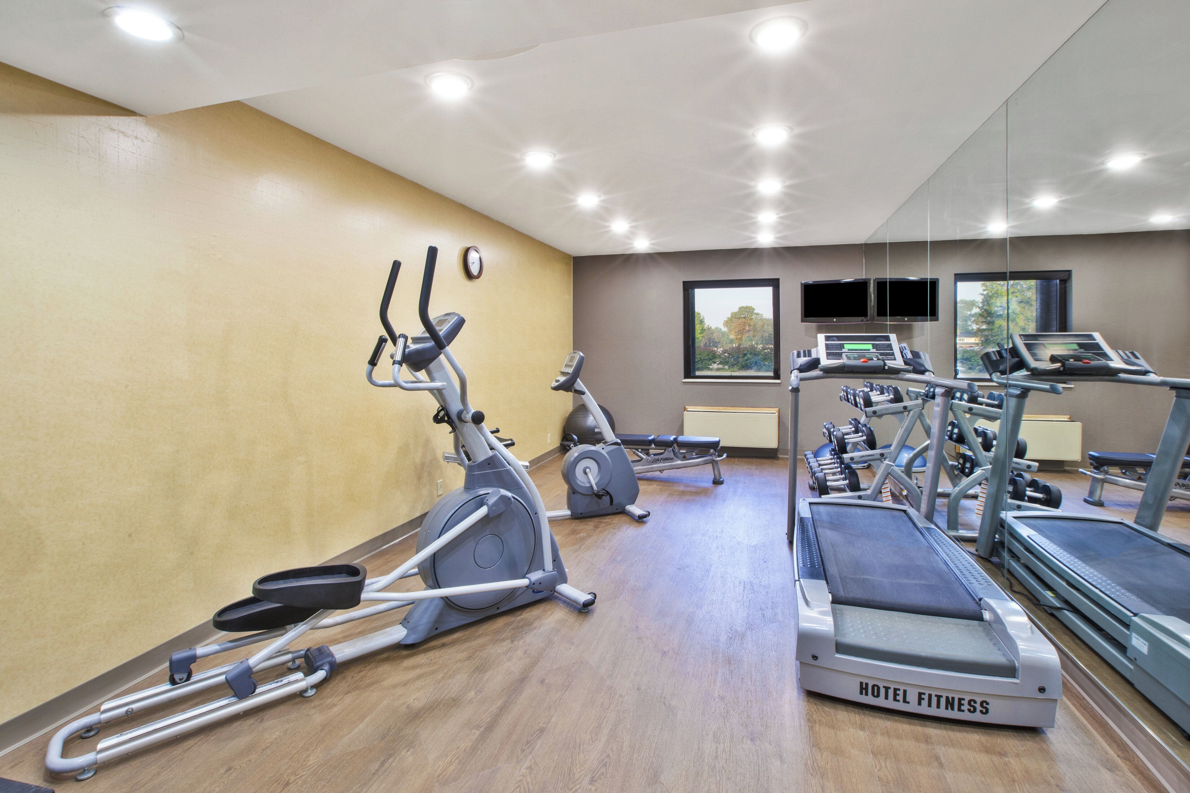 Gimnasio de hotel con cintas de correr, elípticas y pesas libres.