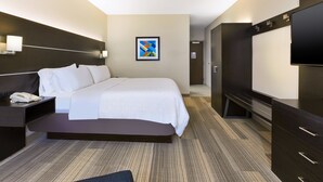 Een moderne hotelkamer met een groot bed, een bureau met telefoon, een flatscreen televisie en een donkere houten garderobe.