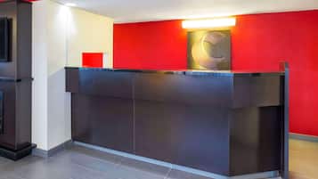 A reception desk with a red accent wall, a modern design, and a flat-screen TV mounted on the wall.