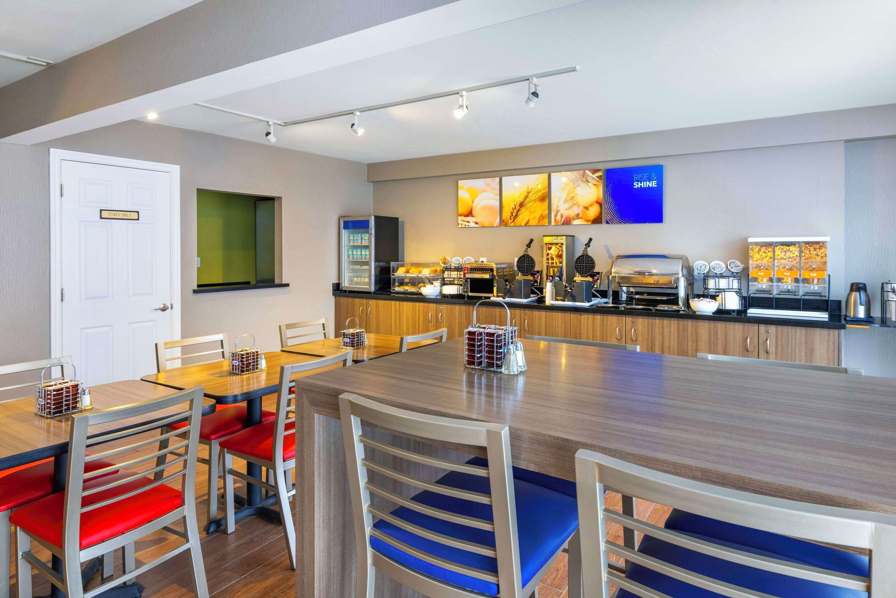 Una cucina moderna con un piano di lavoro in legno, un angolo caffè e un'area pranzo con sedie rosse e blu.