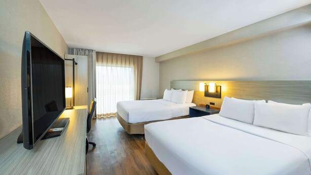 Habitación de hotel con dos camas, televisión y escritorio.