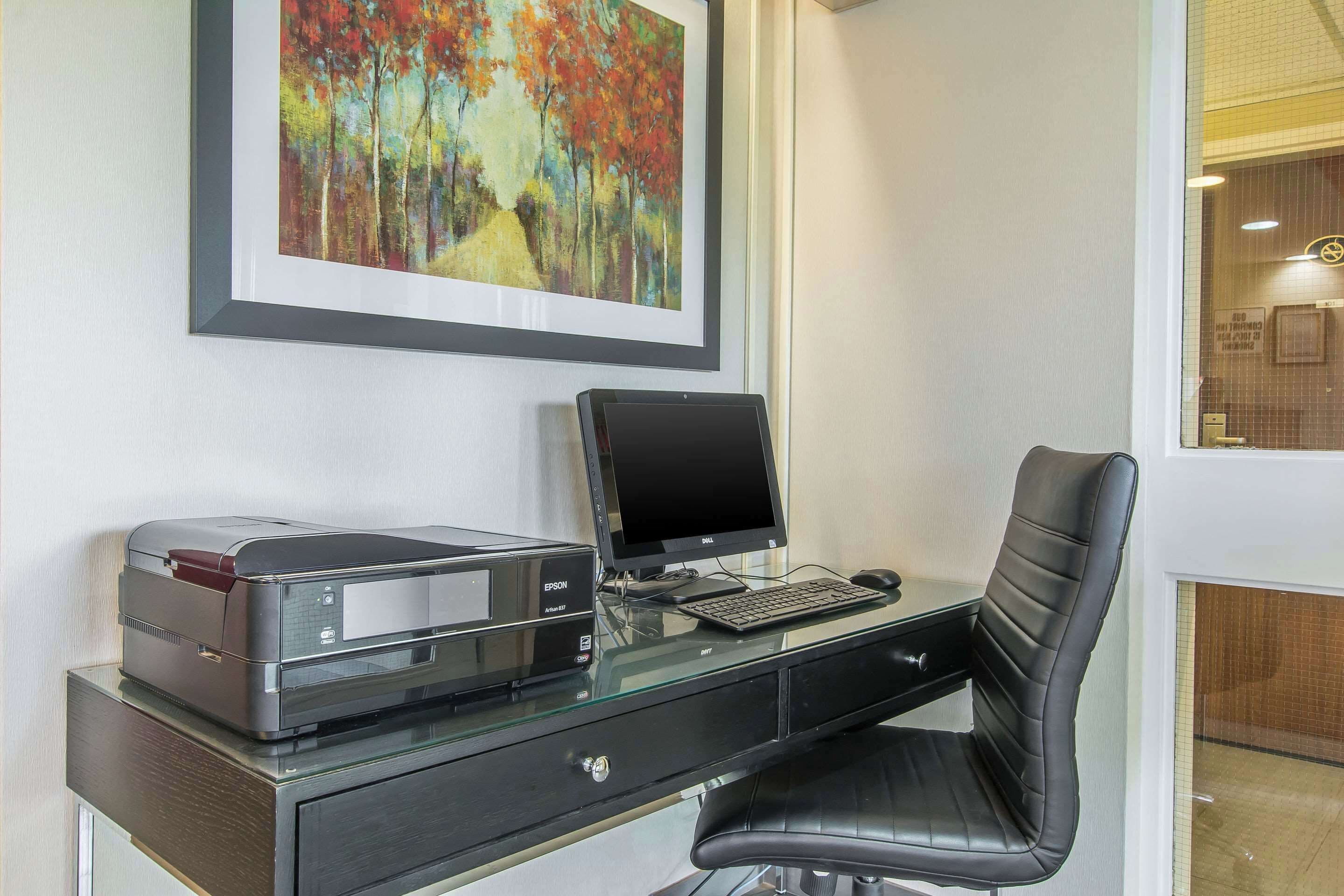 A modern office desk with an Epson printer, a Dell monitor, and a black chair.