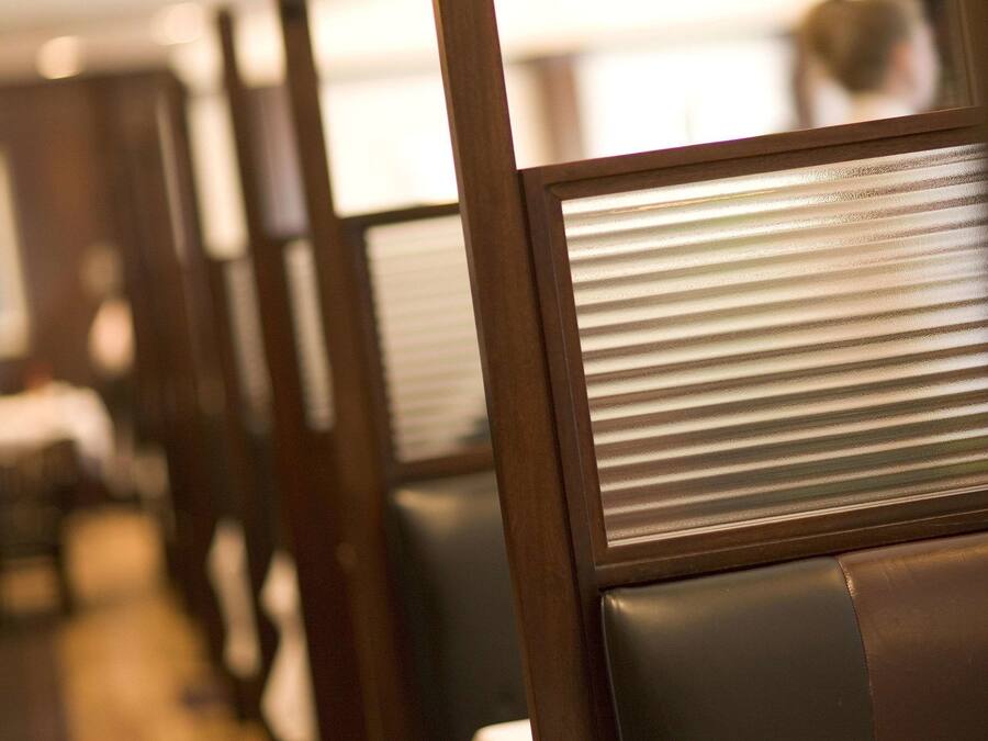 A row of wooden chairs with metal backrests in a restaurant setting.